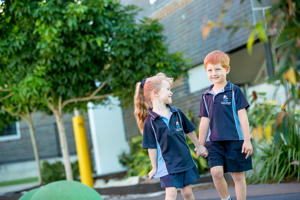 Two primary aged students holding hands and walking.